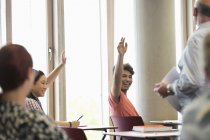 Estudantes universitários sorrindo levantando as mãos no seminário — Fotografia de Stock