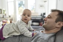 Portrait curious baby daughter laying on father?s chest — Stock Photo