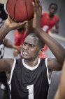 Enfocado joven jugador de baloncesto masculino disparando la pelota - foto de stock