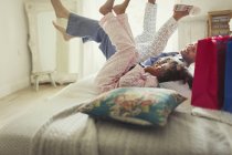 Father and daughters in pajamas kicking legs on bed — Stock Photo