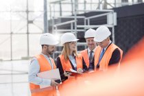 Foreman and engineers discussing paperwork at construction site — Stock Photo