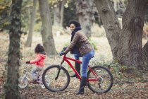Мати і дочка катаються на велосипеді в осінньому лісі — стокове фото