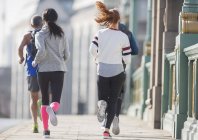 Corridori che corrono sul marciapiede urbano soleggiato — Foto stock
