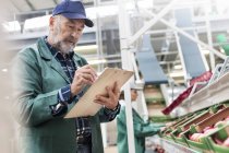 Manager mit Klemmbrett inspiziert Äpfel in Lebensmittelverarbeitungsanlage — Stockfoto