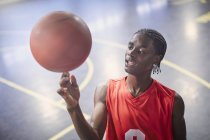 Jovem jogador de basquete masculino girando basquete na quadra — Fotografia de Stock