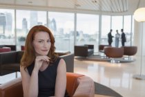 Portrait confident businesswoman with red hair in urban highrise office lounge — Stock Photo