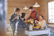 Friends eating and talking at cabin table — Stock Photo