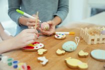 Close up mother and daughter decorating Easter eggs and cookies — Stock Photo
