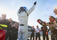 Команда Формулы-1 и пилот аплодируют, празднуя победу на спортивной трассе — стоковое фото