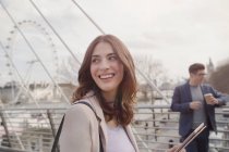 Mulher sorridente andando na ponte urbana perto de Millennium Wheel, Londres, Reino Unido — Fotografia de Stock