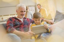 Father and son bonding, using digital tablet on sofa — Stock Photo