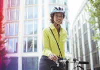 Бізнес-леді штовхає велосипед у місто — стокове фото