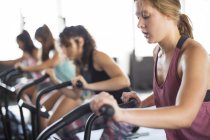Young woman using elliptical bike in exercise class — Stock Photo