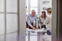 Architects reviewing, discussing blueprints in conference room meeting — Stock Photo