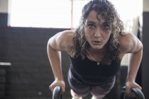 Retrato determinada jovem mulher fazendo flexões com equipamentos no ginásio — Fotografia de Stock