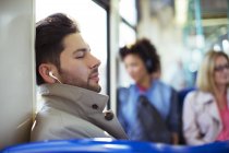 Empresário cochilando e ouvindo fones de ouvido no trem — Fotografia de Stock
