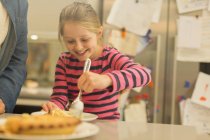 Sorrindo, menina ansiosa servindo torta na cozinha — Fotografia de Stock