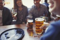 Друзі п'ють пиво і вино за столом у барі — стокове фото