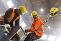 Steel workers fastening crane hook to steel in factory — Stock Photo