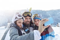 Skier friends taking selfie with camera phone in snowy field — Stock Photo