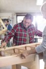 Male carpenters examining wood boat in workshop — Stock Photo