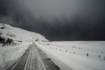 Road through snow covered landscape below stormy sky, Vik, Iceland — Stock Photo