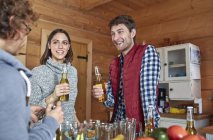 Friends drinking beer and hanging out in cabin kitchen — Stock Photo