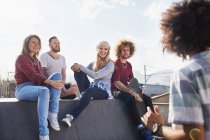 Friends hanging out and talking at sunny skate park — Stock Photo