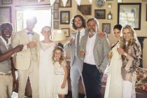 Ritratto di giovane coppia con ospiti e flauti di champagne al ricevimento di nozze — Foto stock