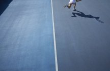 Тени теннисистки, бегущей на солнечном синем теннисном корте — стоковое фото