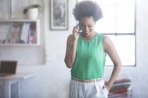Портрет женщины с черными кудрявыми волосами, разговаривающей по мобильному телефону — стоковое фото