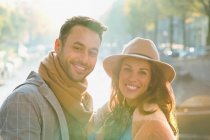 Retrato sonriente pareja joven a lo largo del soleado canal de otoño - foto de stock