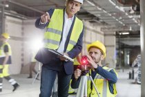 Male foreman and engineer with theodolite at construction site — Stock Photo