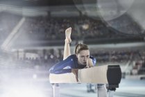 Female gymnast practicing on balance beam in arena — Stock Photo