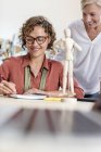 Female design professionals with artist?s figure sketching in office — Stock Photo