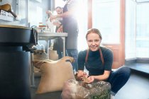 Portrait smiling female coffee roaster inspecting coffee beans — Stock Photo
