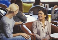 Mulheres sorridentes amigos conversando no bar — Fotografia de Stock