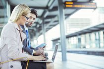 Business people using laptop at train station — Stock Photo