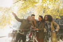 Friends with bicycles along sunny autumn canal — Stock Photo