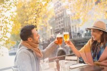 Young couple toasting beer glasses at urban autumn sidewalk cafe, Amsterdam — Stock Photo