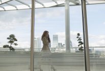 Бізнес-леді розмовляє по мобільному телефону на міському балконі з видом на місто — стокове фото