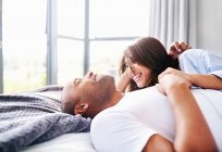 Couple souriant posant et câlinant sur le lit — Photo de stock
