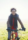 Retrato sorrindo mulher bicicleta equitação no ensolarado parque grama — Fotografia de Stock