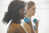Smiling woman doing biceps curls in exercise class gym studio — Stock Photo