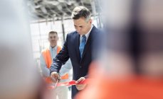 Businessman cutting ribbon at new construction site ceremony — Stock Photo