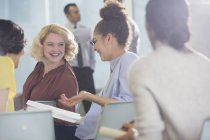 Lächelnde Geschäftsfrauen diskutieren Papierkram im Konferenzpublikum — Stockfoto