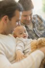 Male gay parents holding baby son — Stock Photo