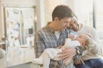 Affectionate male gay parents holding baby son with bottle — Stock Photo