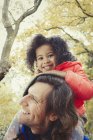 Portrait smiling father father carrying daughter on shoulders in autumn park — Stock Photo