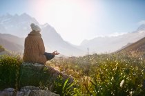 Junge Frau meditiert auf Felsen in sonnigem, abgelegenem Tal — Stockfoto